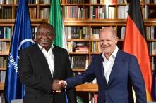 South African President Cyril Ramaphosa shaking hands with the German Chancellor Olaf Scholz with the Group of 7 Germany Presidency, South African and German flags behind them.