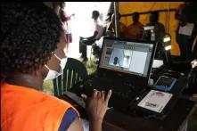 A Zimbabwean election official enters details of a woman who had come to register to vote on the outskirts of Harare