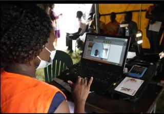 A Zimbabwean election official enters details of a woman who had come to register to vote on the outskirts of Harare